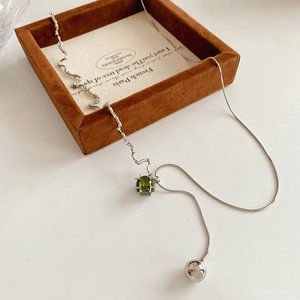 Detailaufnahme der silbernen Schlangenkette mit grünem Zirkonia und polierter Perle