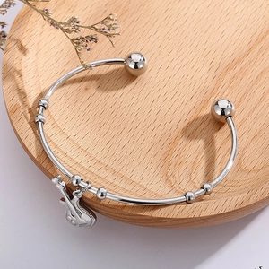 Detail shot of silver titanium guitar pendant bracelet on a rustic wooden tray