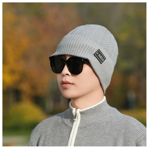 Detail view of grey knit beanie with FARDI letter patch and short brim on a male model