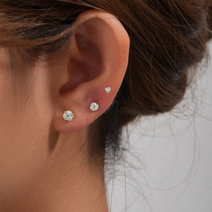Macro detail of three graduated silver love knot earrings on a model ear