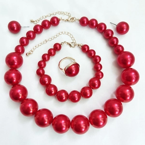 Detailed set of red pearl necklace, bracelet, earrings and ring on white fabric