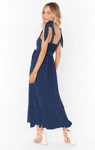 Detail of navy blue sleeveless dress featuring shoulder bow ties and smocked back panel