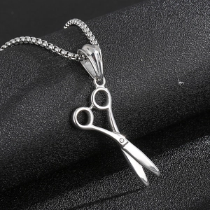 Vue macro d'un pendentif de ciseaux en acier inoxydable argenté sur chaîne box