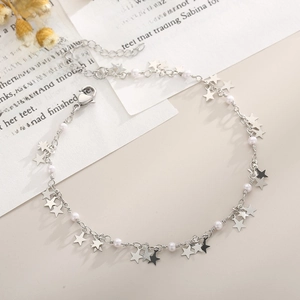 Detailed shot of silver star anklet with white pearls and lobster clasp on vintage paper