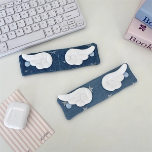 Detail of denim cable organizer straps with white plush wings and blue buttons
