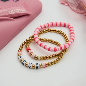 Details von stapelbaren LOVE-Armbändern mit Goldperlen und rosa Polymer-Ton-Scheiben