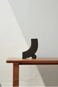 Detail der mattschwarzen Keramikvase mit minimalistischem Design auf einer Holzbank