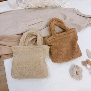 Borse a mano in sherpa beige e caramello esposte con abiti invernali coordinati