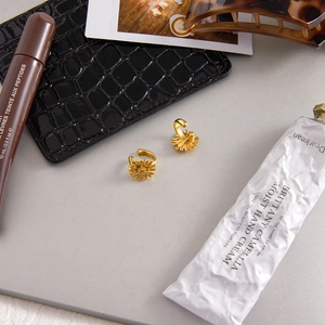 Detail showing vintage gold sunflower ear cuffs arranged with fashion accessories