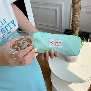 Mint green portable nylon pencil case held by a woman in a lifestyle setting