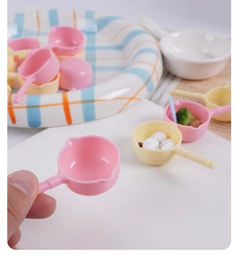 Close-up of mini dollhouse plastic milk pans in pink and yellow for kitchen play