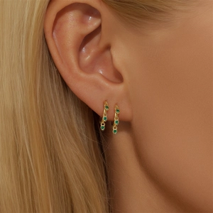 Macro view of gold S925 silver huggie hoops featuring three green zircon stones