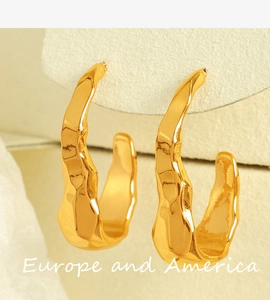 Macro view of 18K gold plated earrings with irregular lava texture on beige background