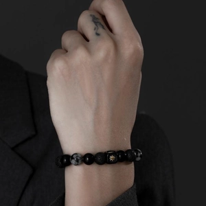 Close-up of men's black agate beaded bracelet with a gold star pattern square bead