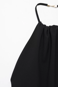 Detailaufnahme des schwarzen Neckholder-Ausschnitts mit goldener Schnalle und Plisseestoff