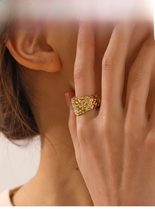 Close-up of a wide hammered texture gold ring with minimalist lava style for women