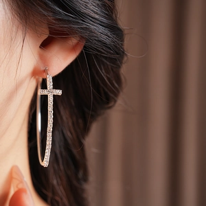 Primo piano di grandi orecchini a cerchio a croce con strass indossati da una modella