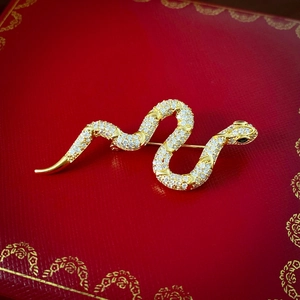 Exaggerated gold plated snake brooch with sparkling white zircons and green gem eyes
