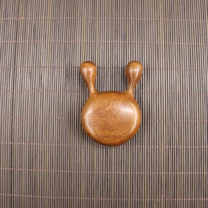 Close-up of polished sandalwood meridian massage tool with five teeth on bamboo mat