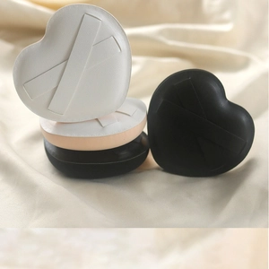 Close-up of heart-shaped makeup puffs in black and white colors on soft silk fabric