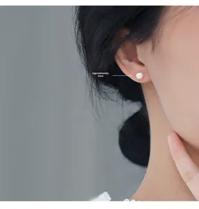Close-up of 7mm round white pearl stud earring worn on model for a minimalist look