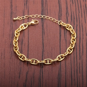 Macro detail of gold-plated pig nose chain bracelet with lobster clasp on wood