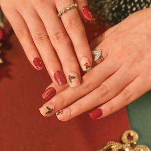 Christmas press-on nails with red glitter and hand-painted festive berry designs