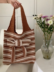 Close-up of brown and beige striped knitted tote bag with a large decorative bow detail