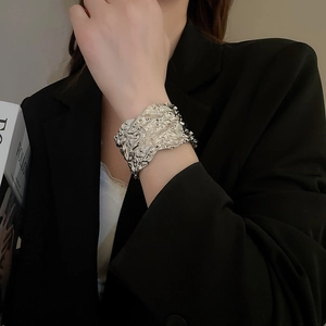 Detail of silver irregular crumpled texture wide open cuff bracelet worn by a model