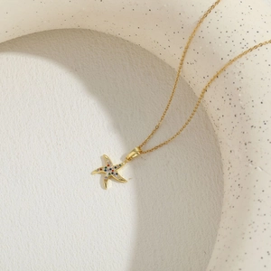 Close-up of a gold necklace featuring a starfish pendant with multicolored zircons