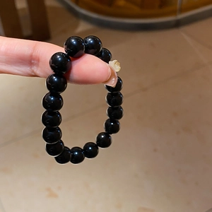 Detailed close-up of obsidian beaded bracelet featuring a single yellow floral accent bead