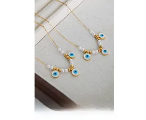 Close-up of gold-plated evil eye necklaces with pearls on a fabric jewelry tray