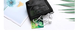 Close-up of a small black mesh organizer bag storing white earphones and cards on a white desk
