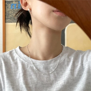 Detailed view of irregular 925 sterling silver beaded necklace on model with silver earrings