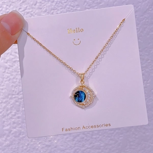 Dettaglio della collana dorata con ciondolo luna e stella con pietra blu e cristalli