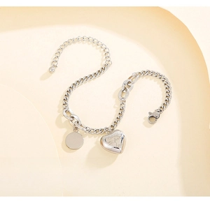 Detail of silver heart charm with Blind for Love engraving on Cuban link bracelet