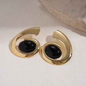Macro detail of retro gold spiral earrings with large oval black gemstone inlay