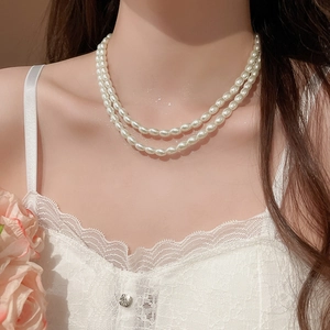 Detail of elegant double-layered pearl necklace worn on neck with white oval beads