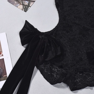 Detail of black lace bodysuit featuring a large velvet bow decoration and high neck