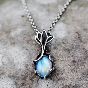 Macro view of vintage silver leaf pendant with blue moonstone on a stone background