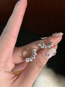 Detail of silver ear cuff featuring inlaid white pearls and sparkling cubic zirconia stones
