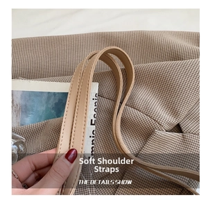 Detail of soft brown leather shoulder strap on a plaid tote bag for daily commute