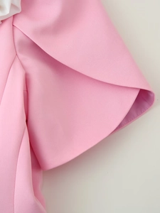 Dettaglio del polsino in tessuto rosa che mostra il taglio a petalo e la trama del blazer