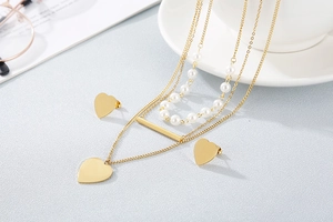 Detailed view of triple-layered gold heart necklace set with pearls and matching earrings