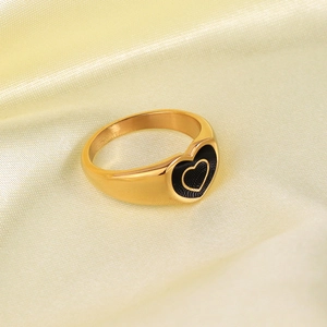 Detail of 18K gold stainless steel ring with black heart design on beige silk cloth