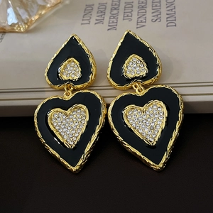 Makroaufnahme der schwarzen Herzohrringe im Vintage-Stil mit Goldrand und Diamanten