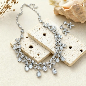 Detail of silver bowknot necklace and earrings set with crystal droplets on stone