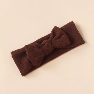 Detail shot of a brown knitted baby headband with a soft textured bow design