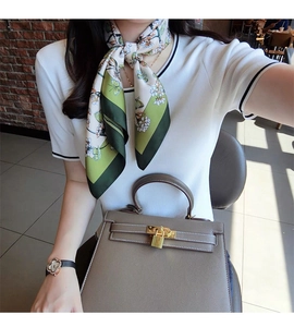 Detail of a floral silk scarf with butterflies tied on a taupe leather handbag handle