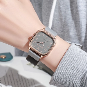 Detail of rose gold square quartz watch with grey silicone strap worn on wrist